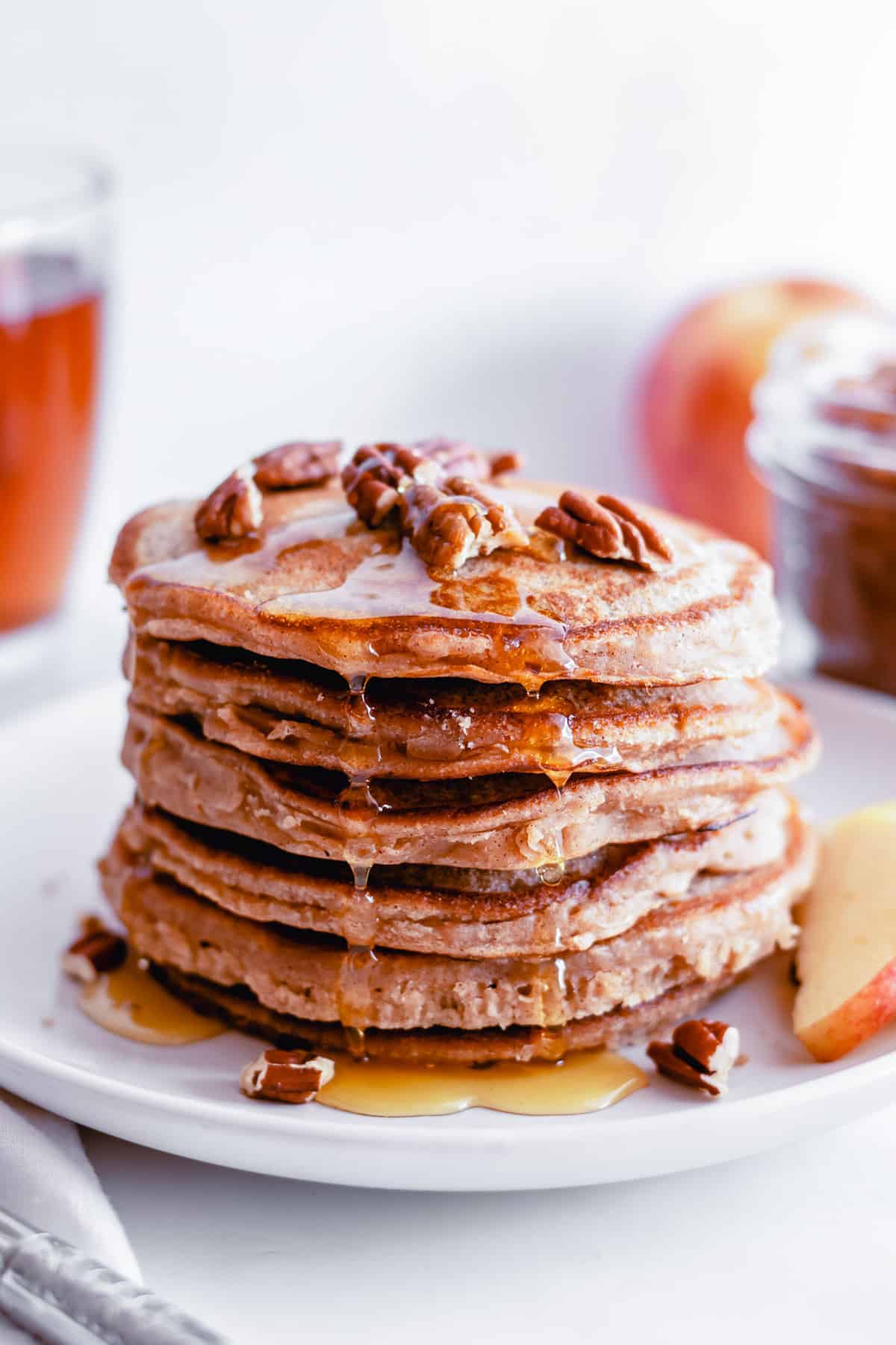 Montón de panqueques de mantequilla de manzana goteando con jarabe y cubiertos con nueces.