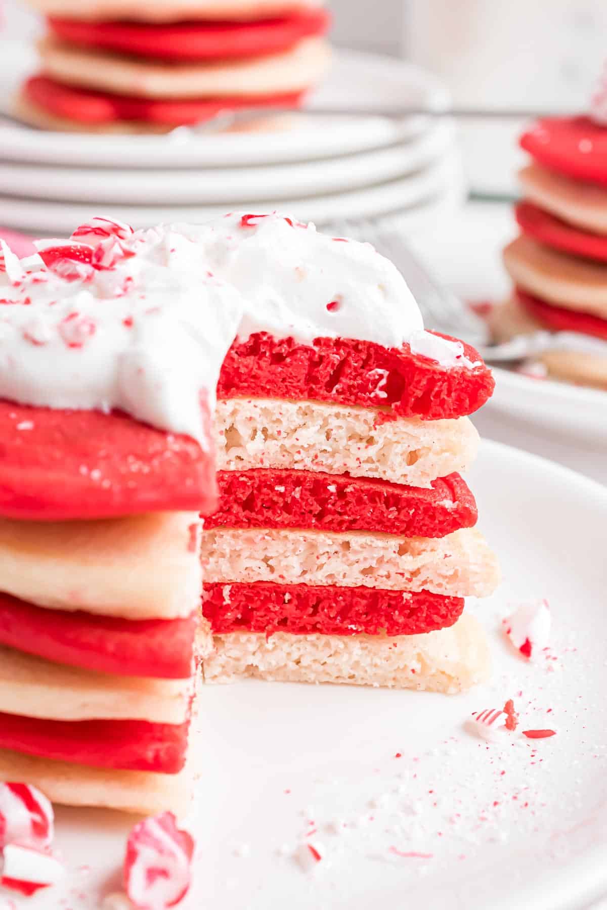 Montón de panqueques rojos y blancos de bastón de caramelo con crema batida.