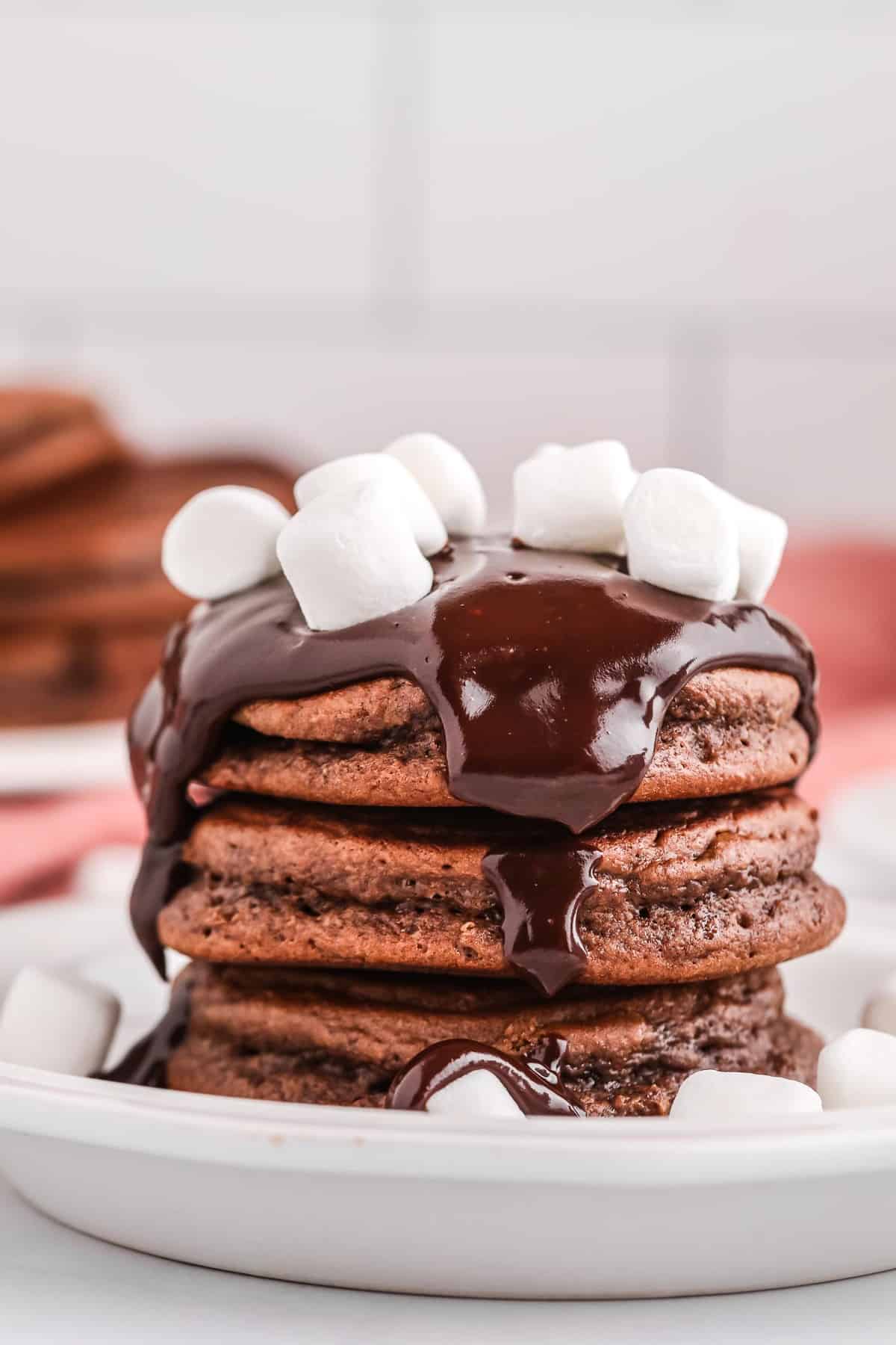 Montón de panqueques de chocolate con ganache de chocolate y malvaviscos.