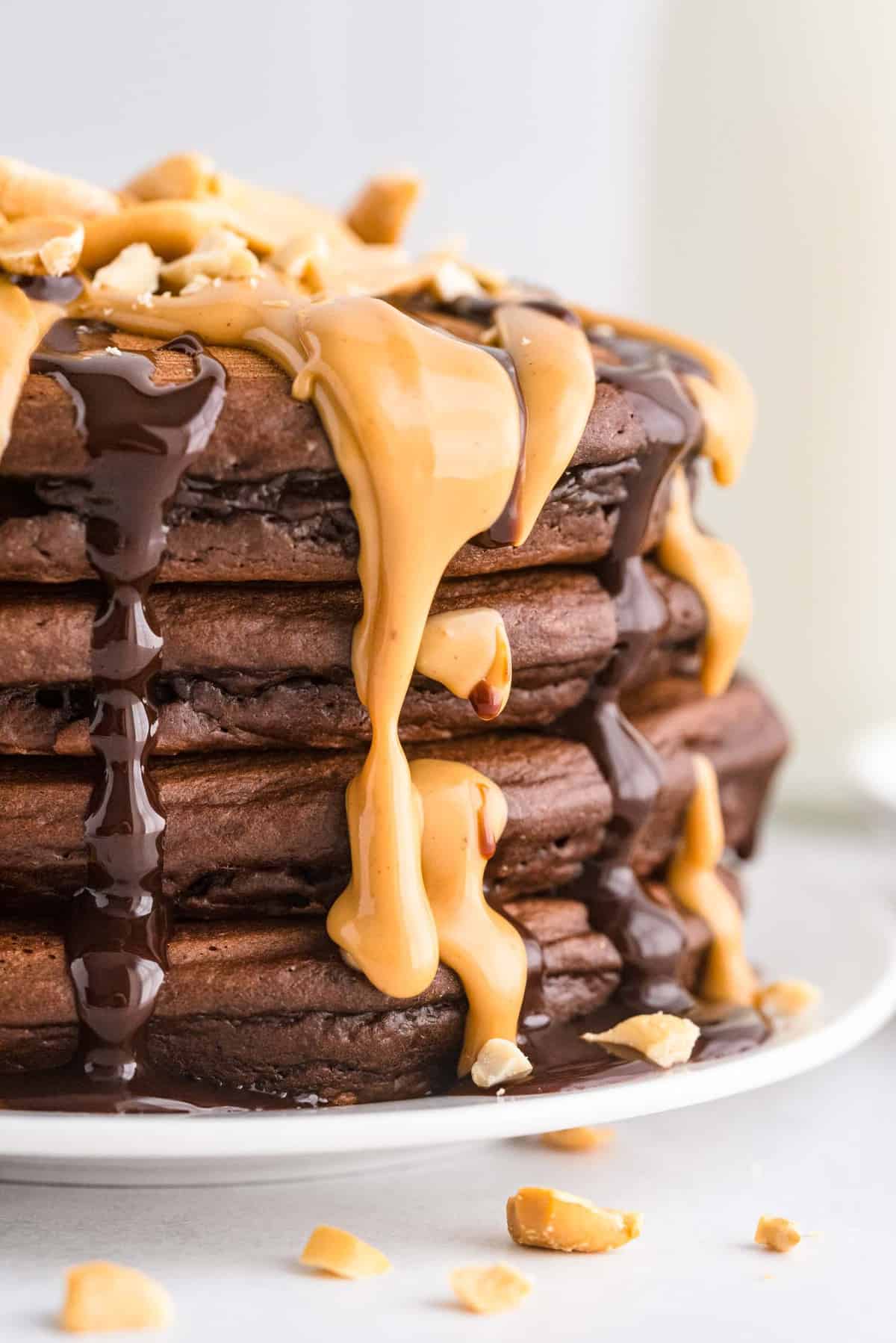 Montón de panqueques de chocolate y mantequilla de maní con coberturas derretidas.