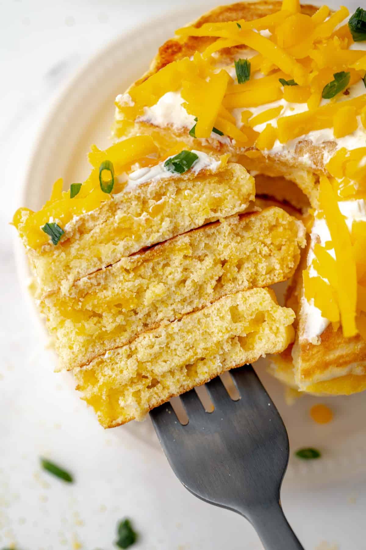Panqueques de pan de maíz con queso en una pila, cortados para mostrar la textura.