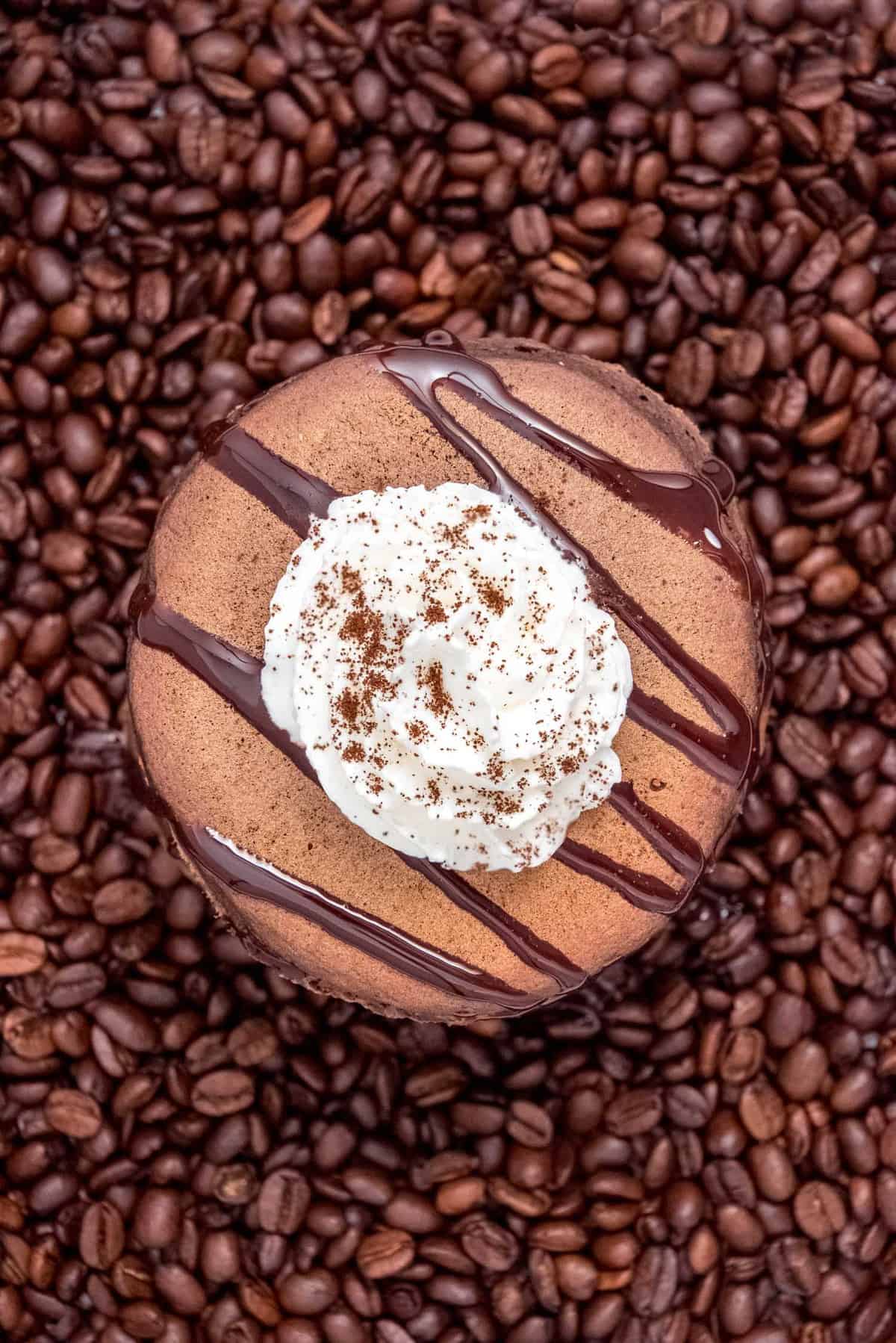Panqueques de chocolate, cubiertos con crema batida y rociados con chocolate, sobre granos de café.