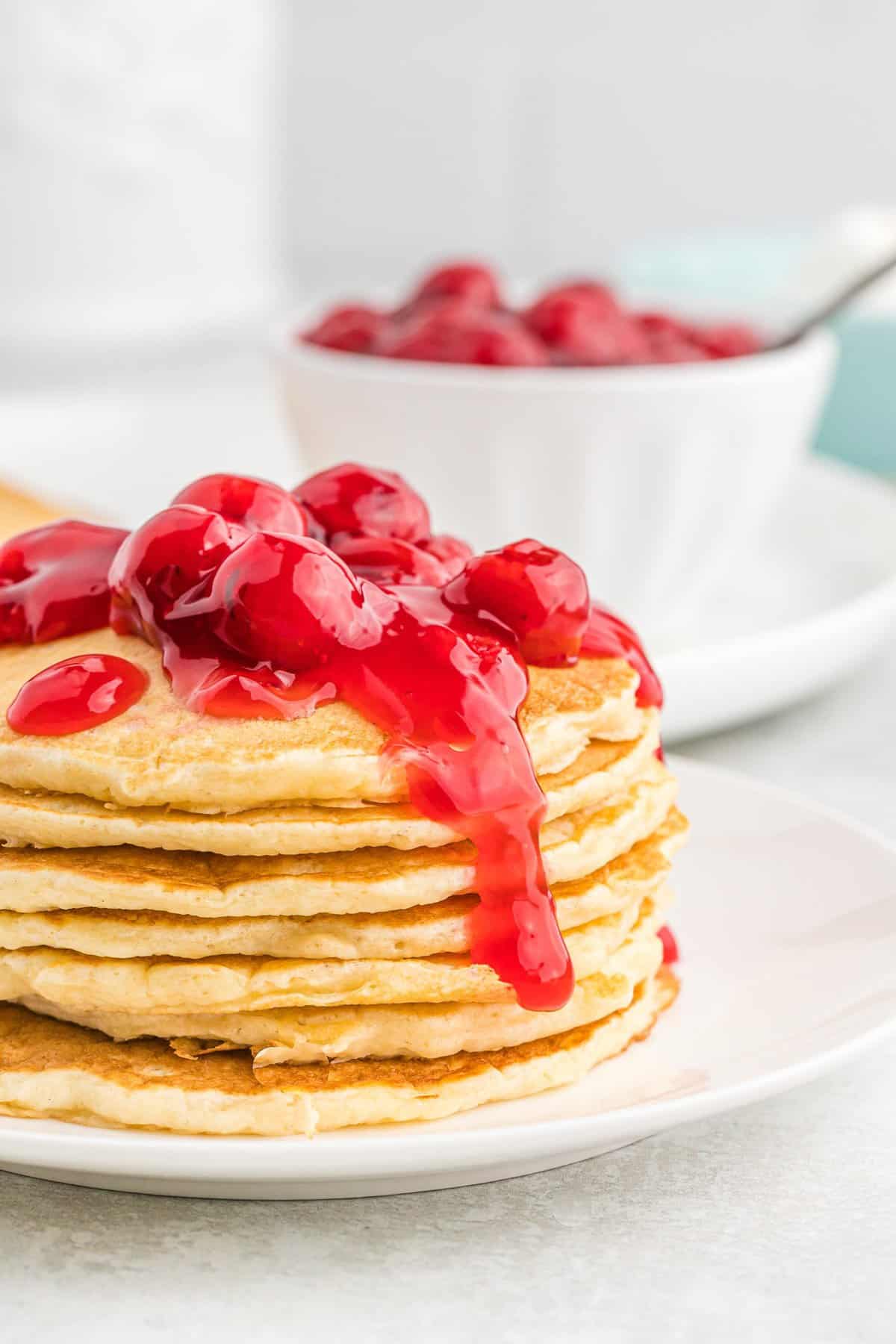 Montón de panqueques de tarta de cereza con cerezas encima.