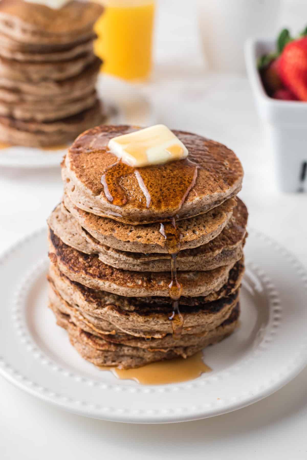 Alto montón de panqueques con mantequilla y jarabe.