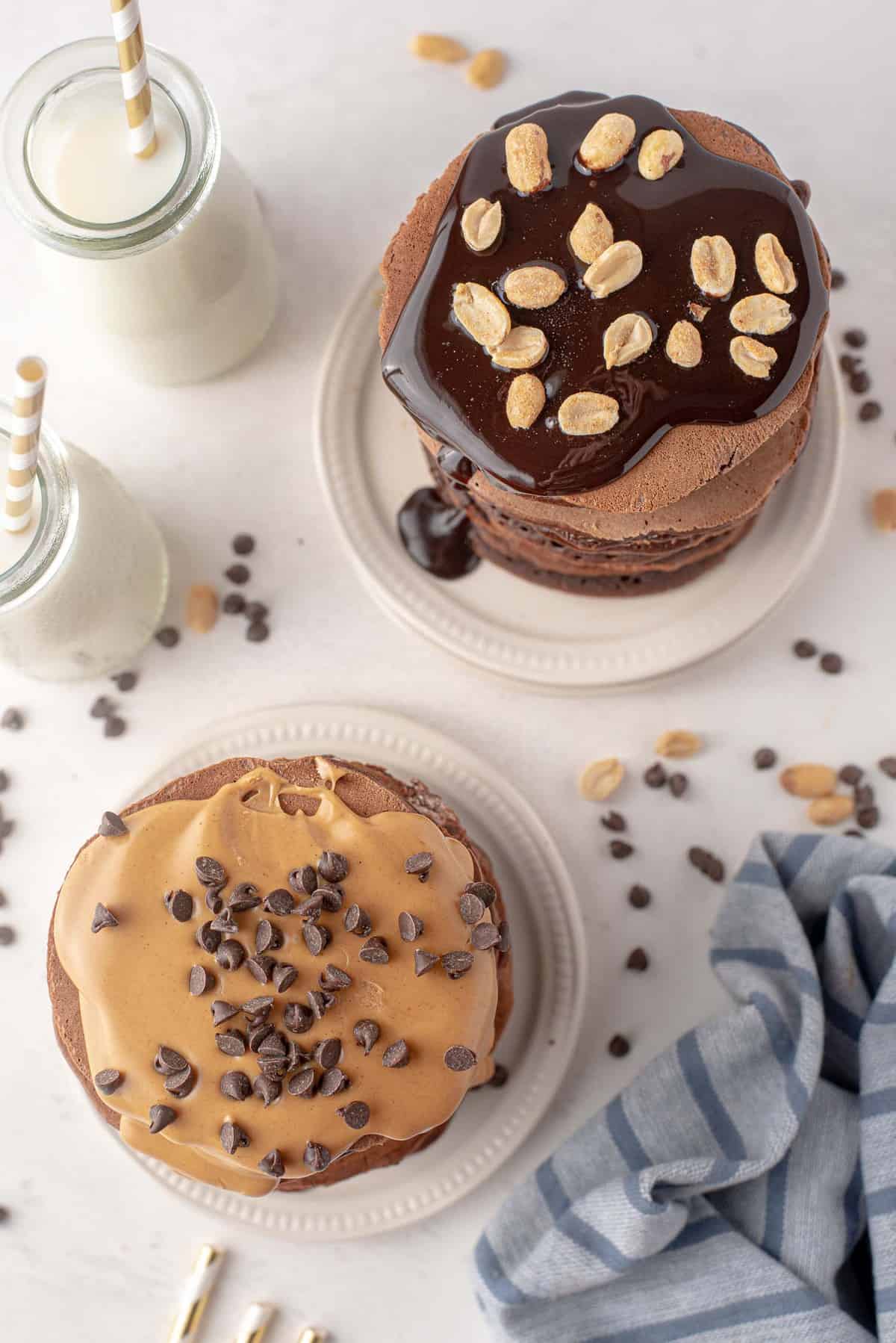 Vista aérea de dos pilas de panqueques de chocolate cubiertos con mantequilla de maní y cacahuetes.
