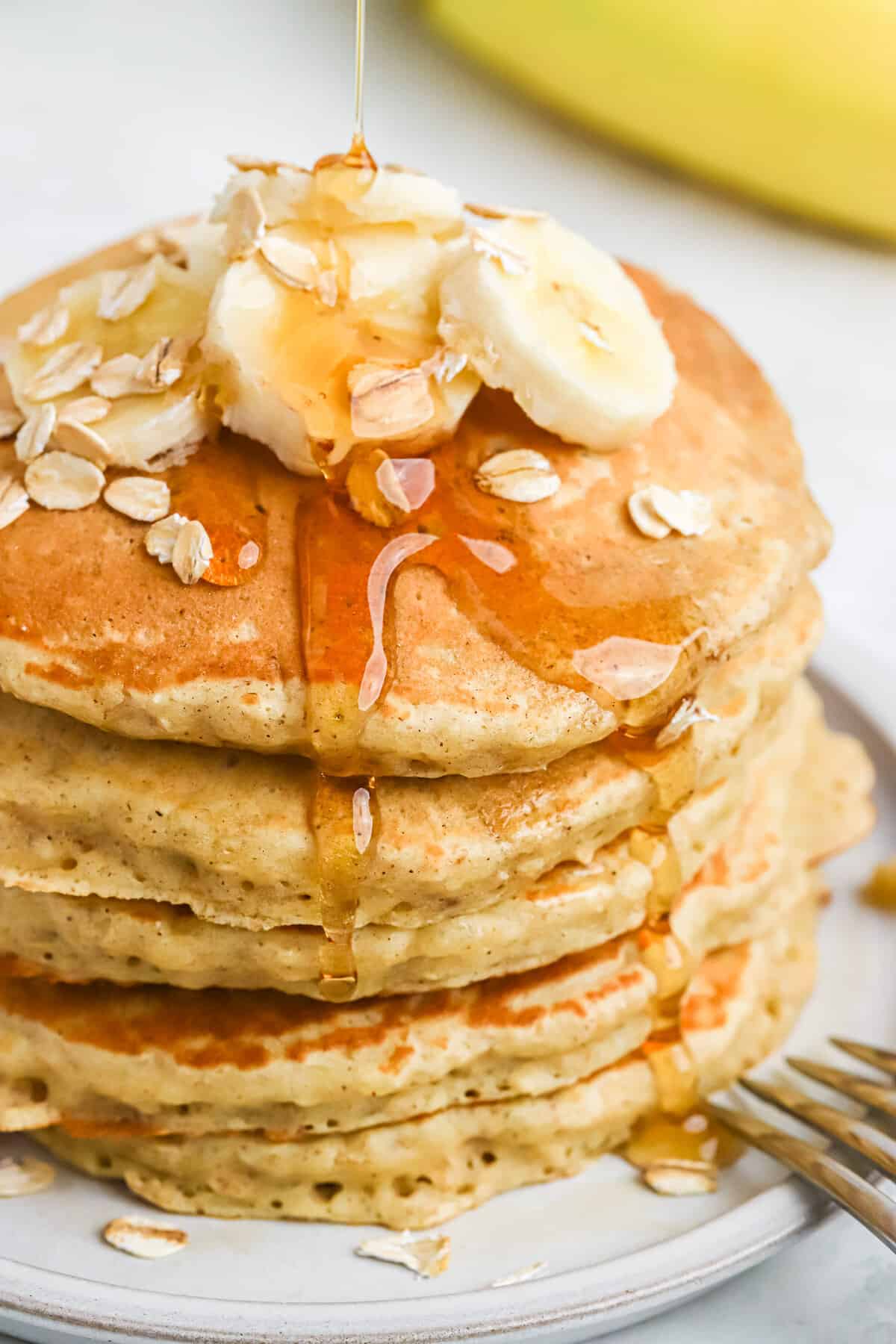Montón de panqueques de avena con plátano y jarabe.