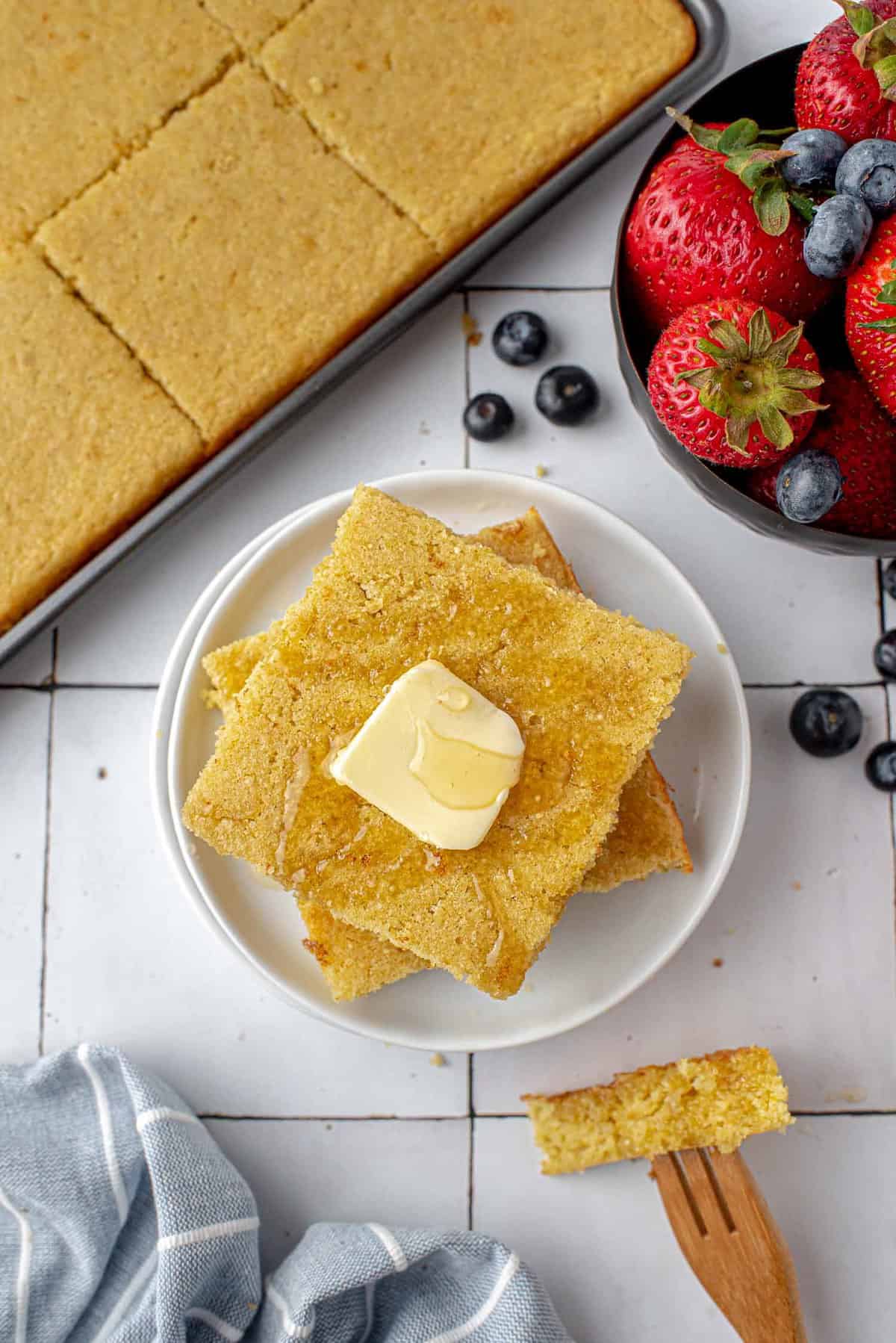 Panqueques sin gluten en bandeja con mantequilla, fruta cerca.