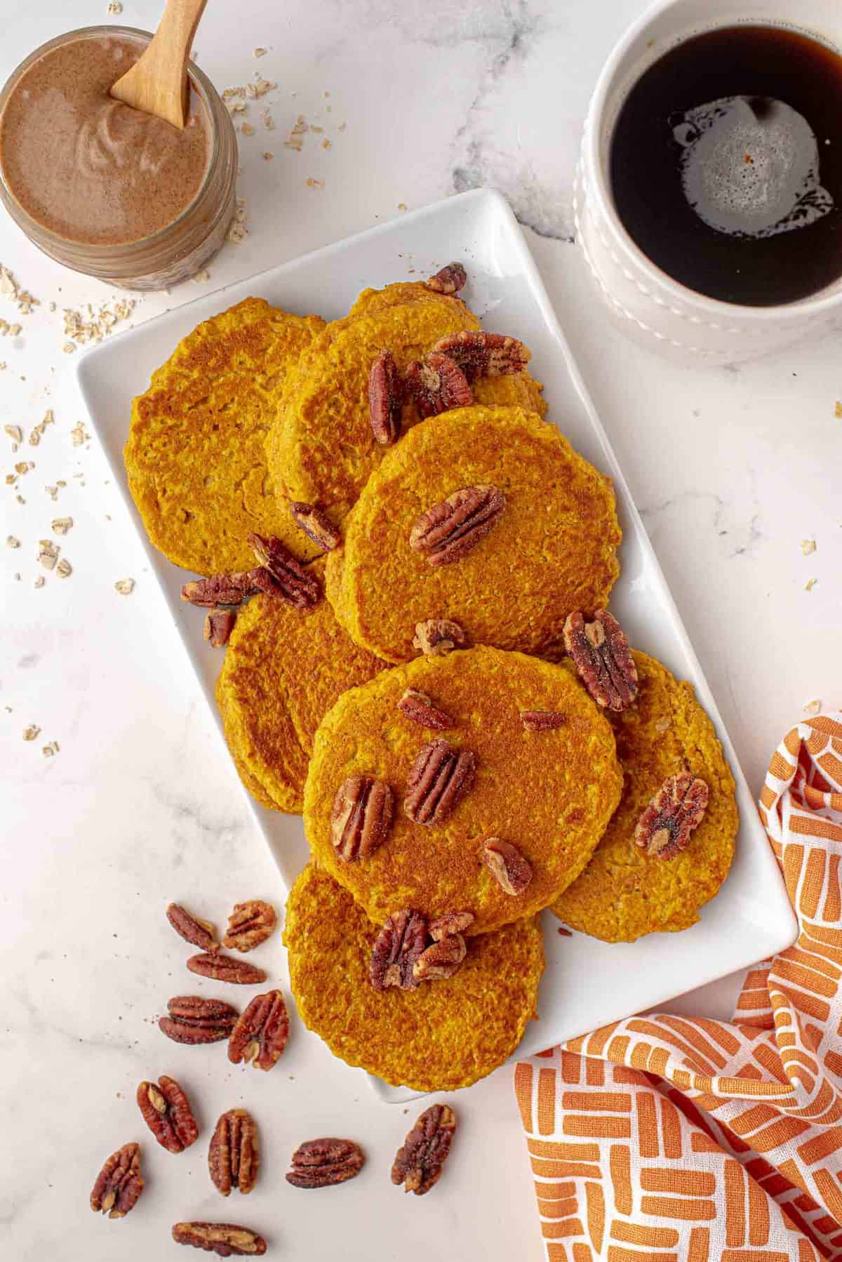 Vista desde arriba de los panqueques de calabaza saludables en una bandeja espolvoreados con nueces.