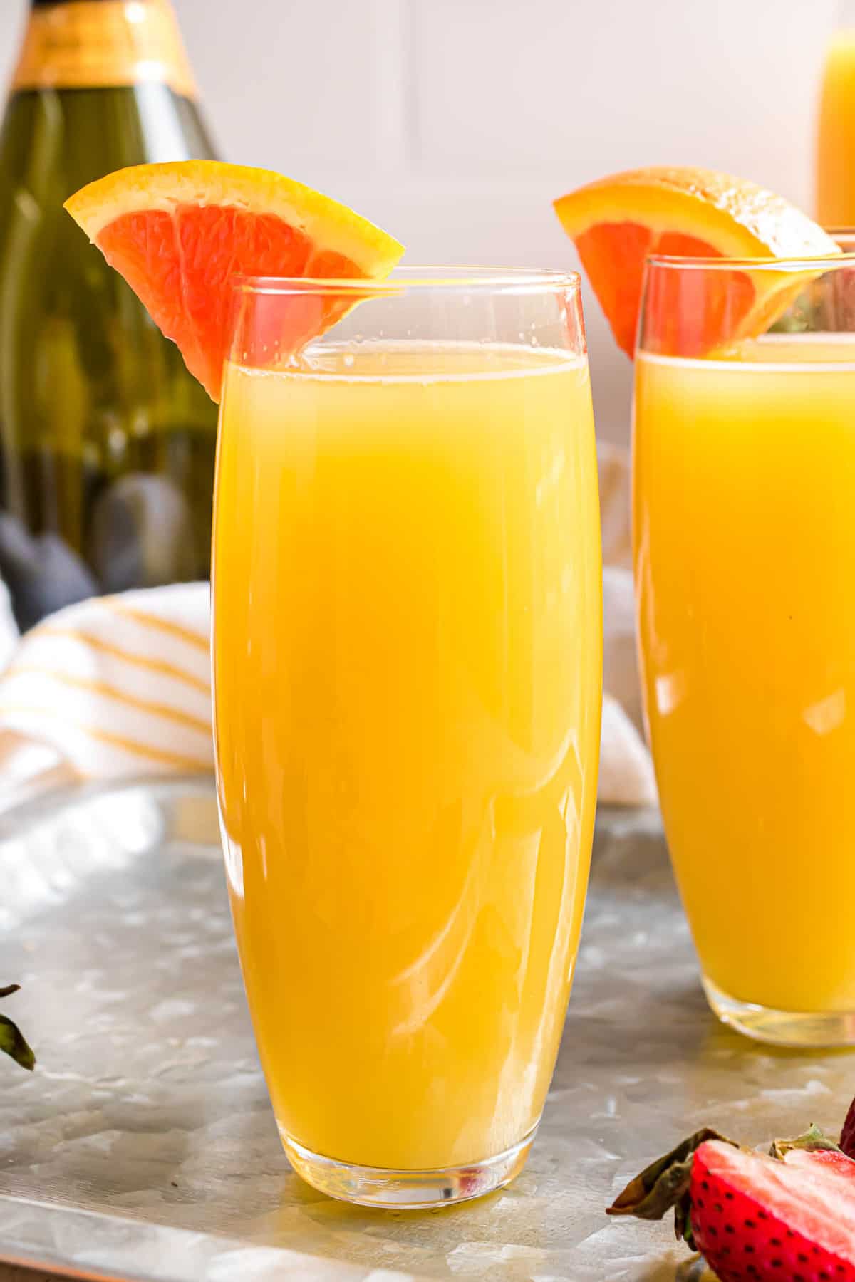 Mimosa de naranja en un vaso sin tallo decorado con una rodaja de naranja.
