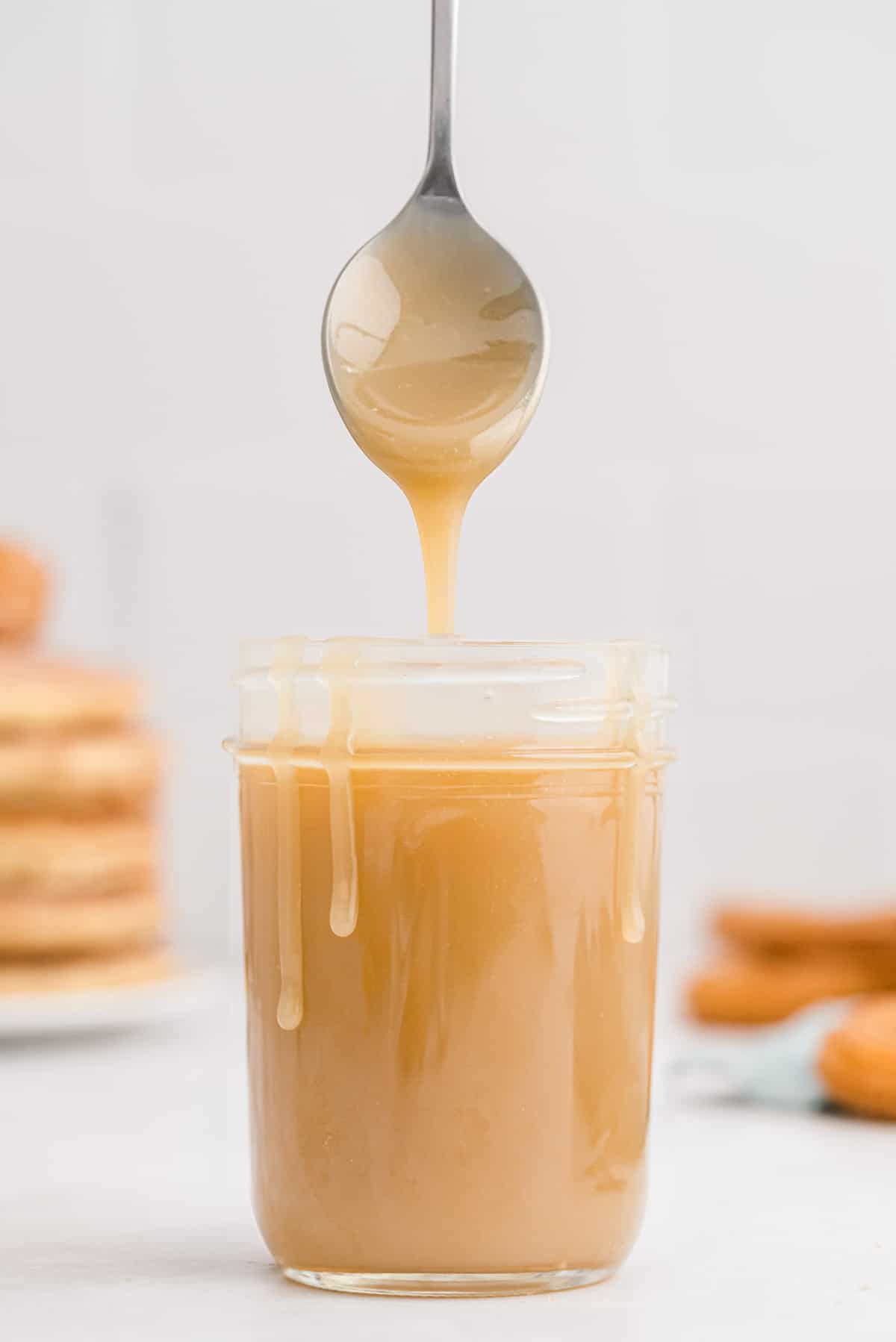 Caramelo en un tarro, goteando por los lados del tarro, una cuchara flotando sobre él.