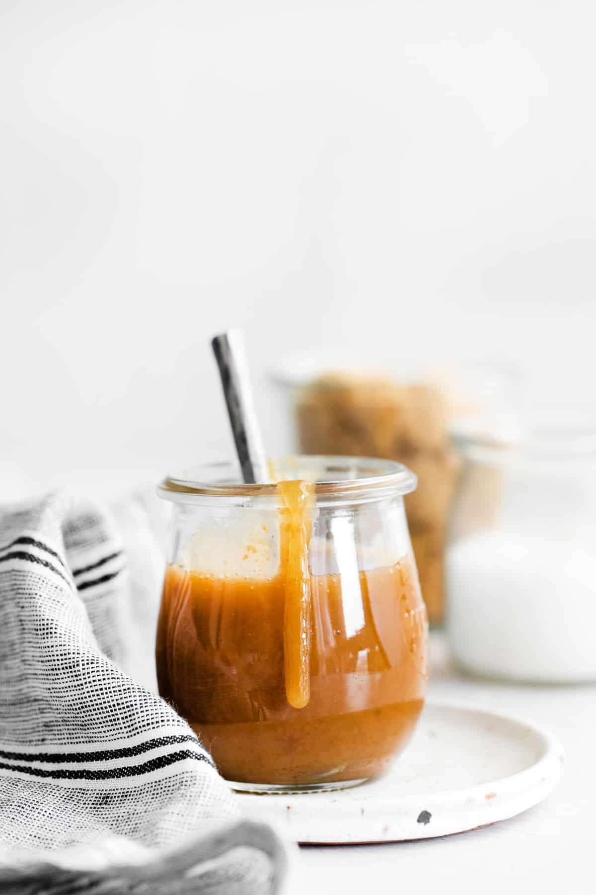 Tarro de caramelo vegano con salsa goteando por el lado del tarro.