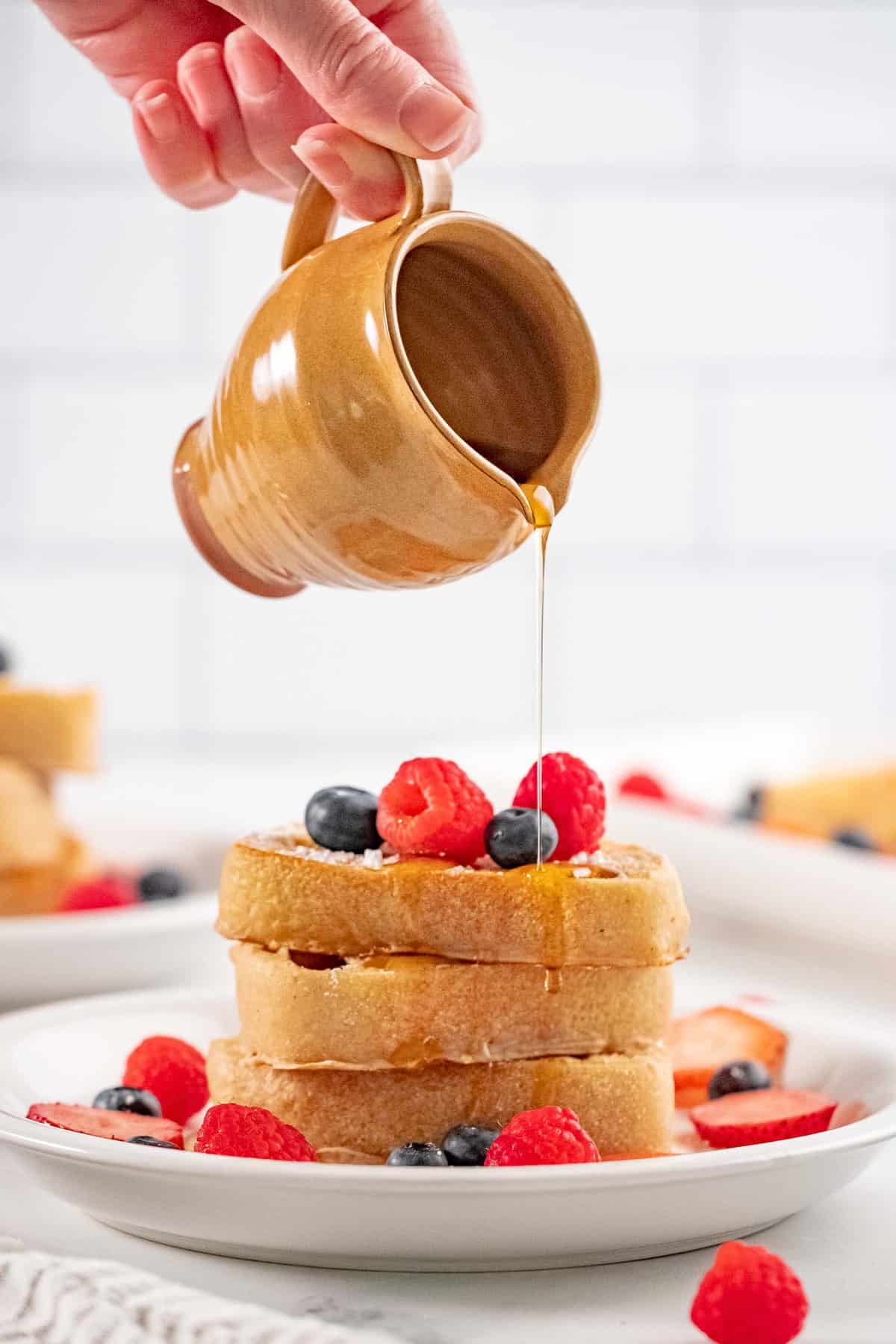 Sirope vertiéndose sobre una pila de tostadas francesas veganas.
