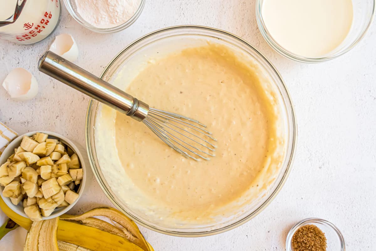 Ingredientes húmedos para los panqueques en un tazón de mezcla de vidrio claro.