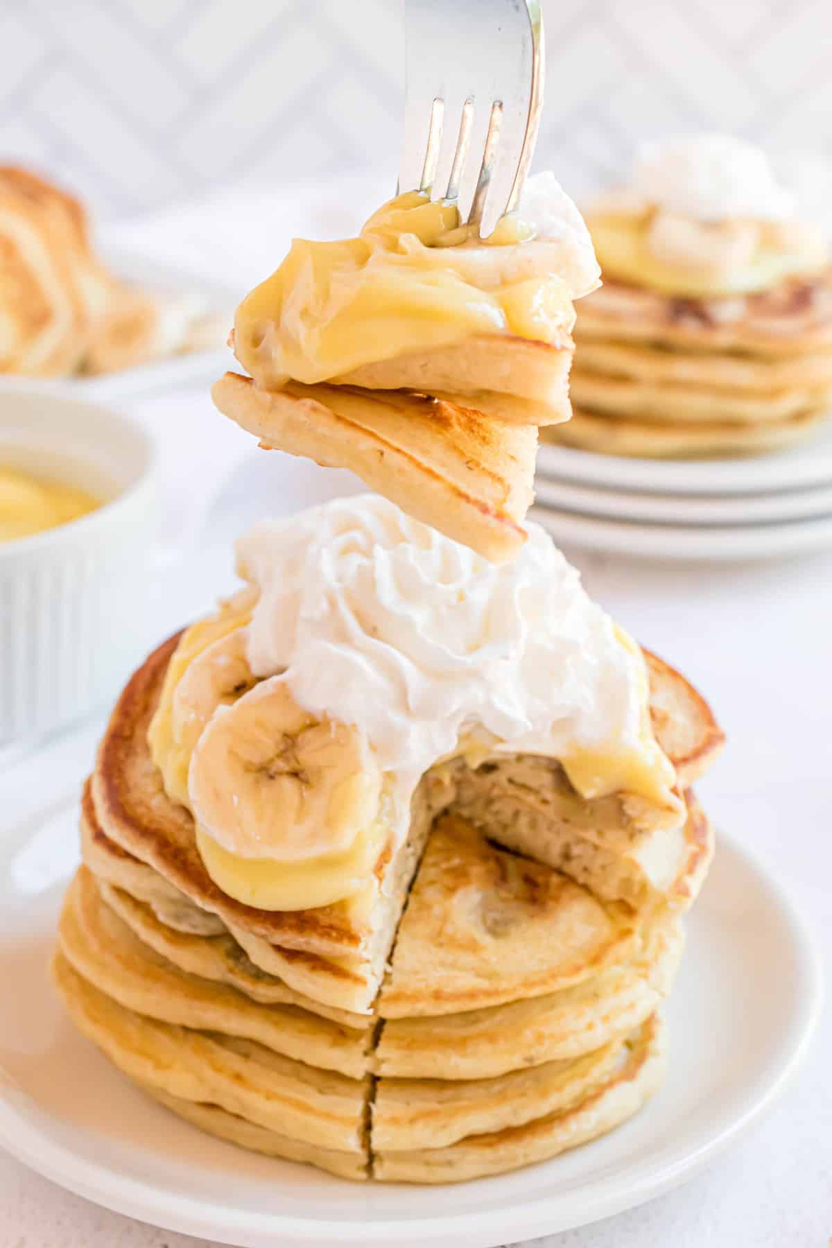 Panqueques de plátano en un tenedor, con una pila detrás.