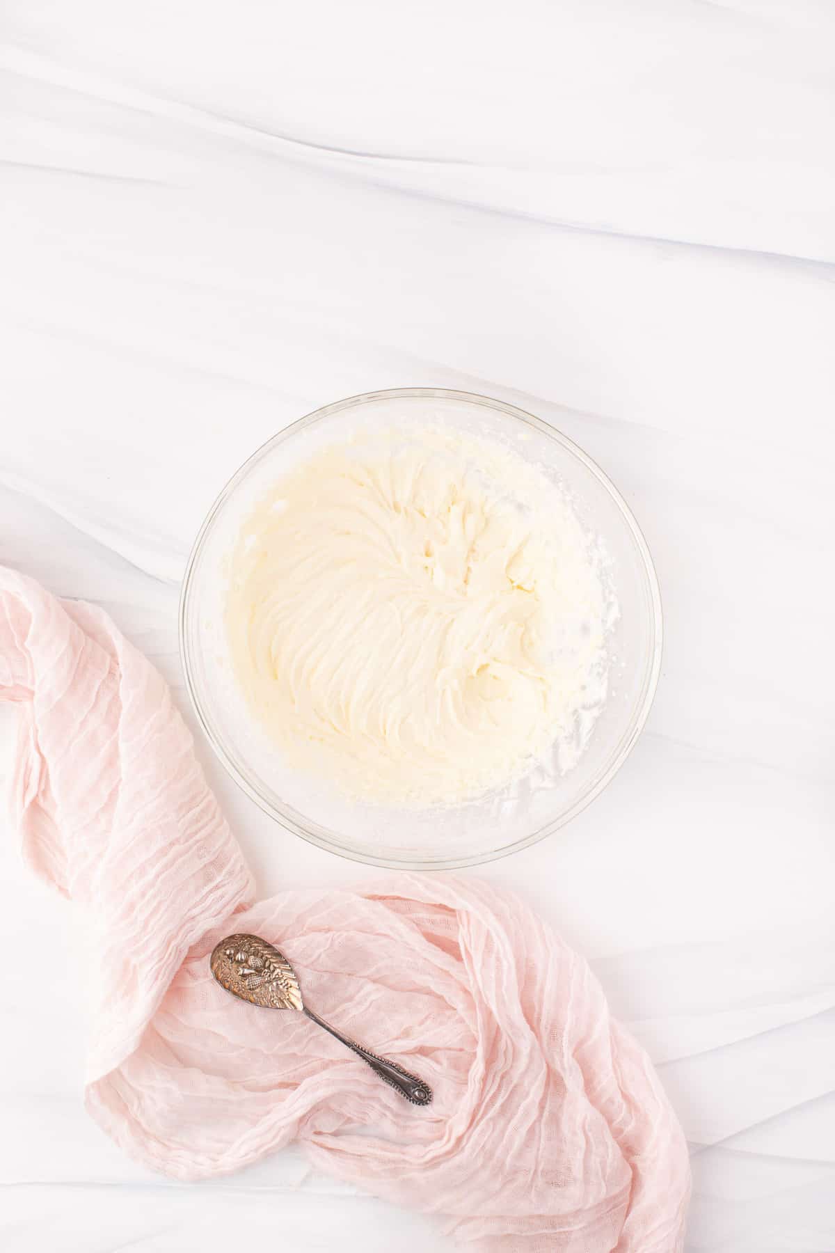 Glaseado de queso crema en un tazón de mezcla de vidrio.
