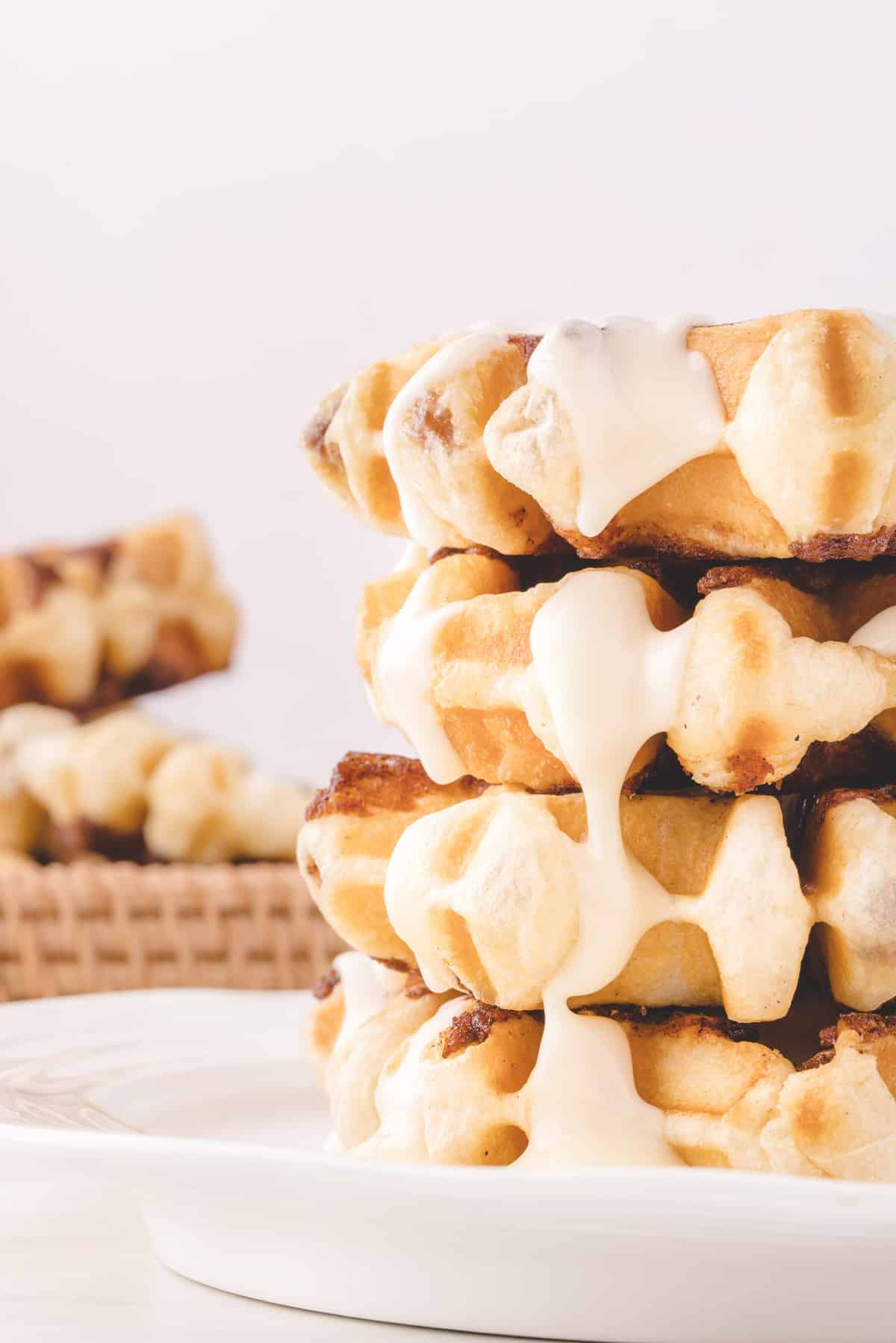 Glaseado de queso crema goteando sobre una pila de panqueques tipo rollo de canela.