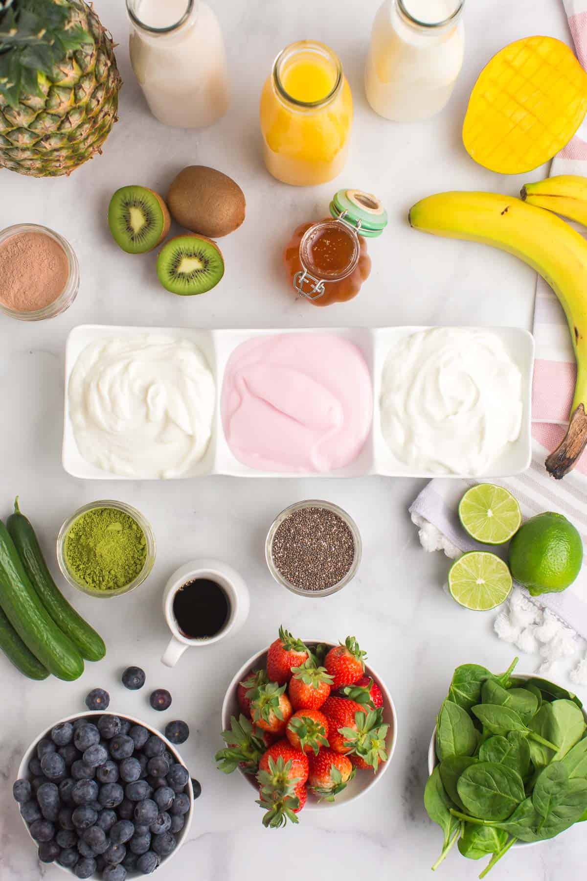 Vista aérea de los ingredientes para batidos que incluyen yogur, frutas, verduras y edulcorantes.