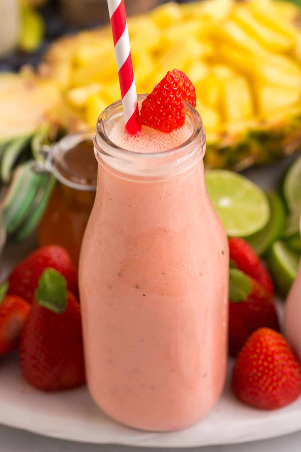 Primer plano de un batido de fresa con fruta fresca de fondo.