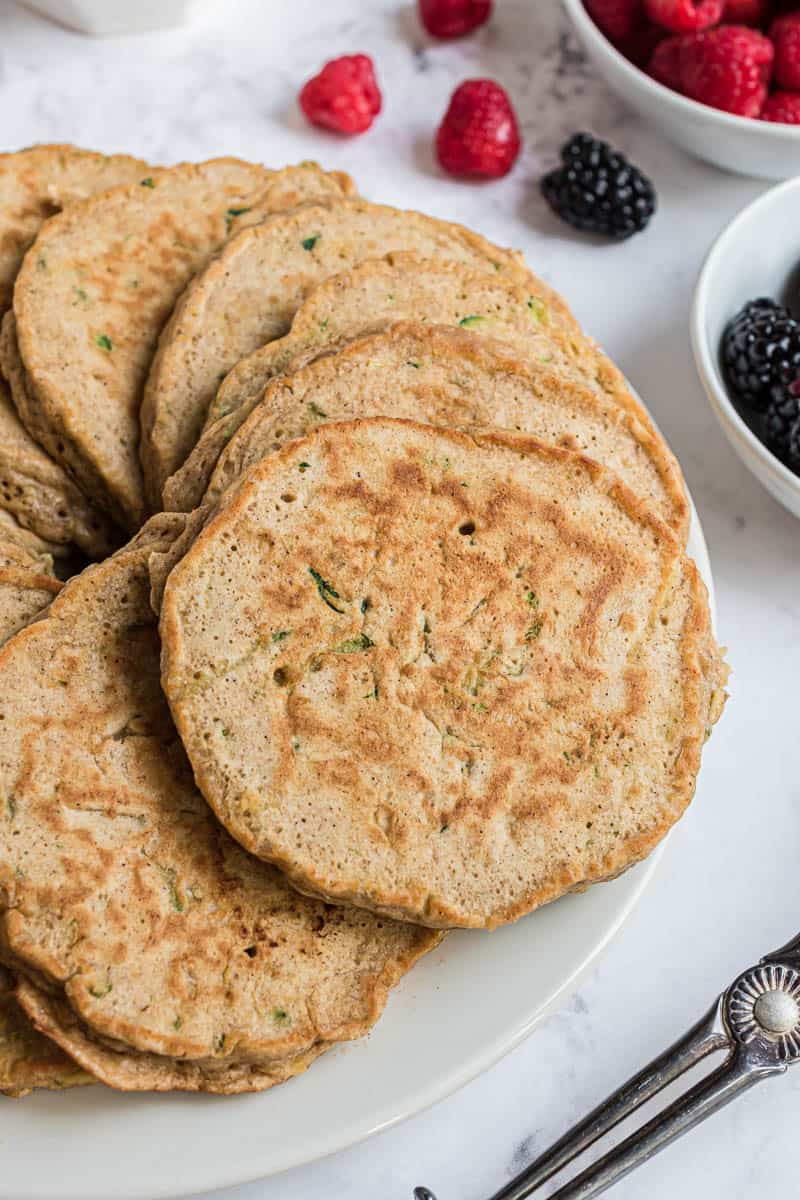 Primer plano de panqueques de pan de calabacín en un plato blanco.