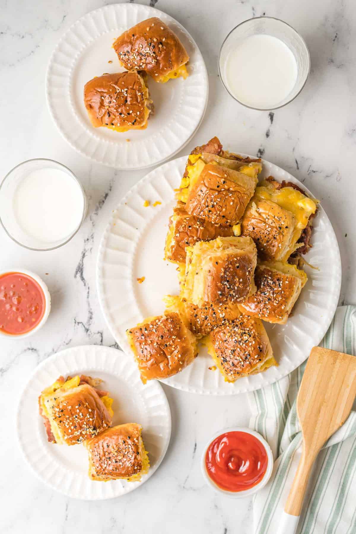 Sliders en tres platos diferentes, con vasos de leche y pequeños tazones de ketchup.