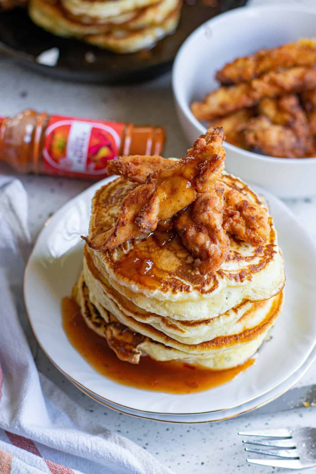 Una pila de panqueques, cubiertos con pollo crujiente y picante.