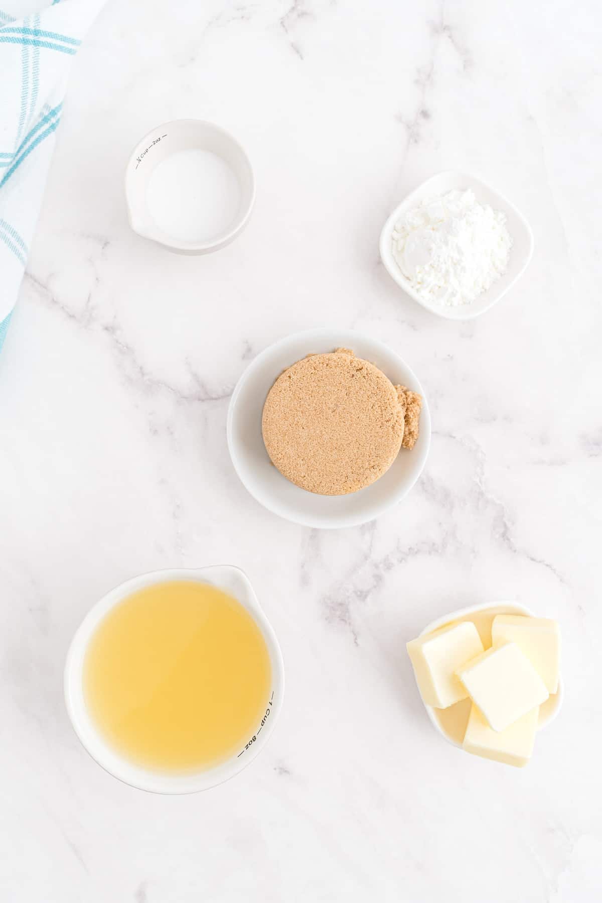 Vista aérea de los ingredientes para la salsa de ron: Mantequilla, azúcar moreno, jugo de piña, maicena, crema de coco.