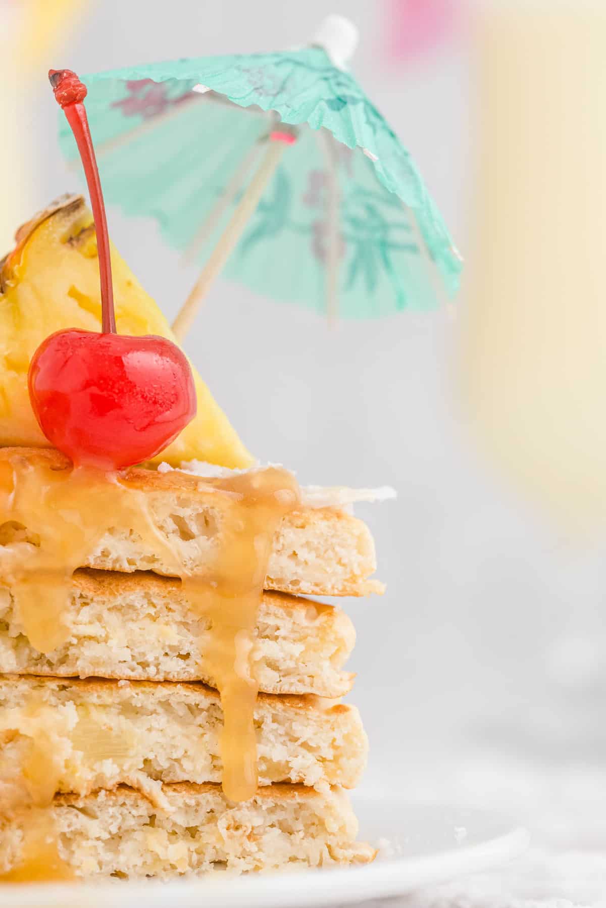 Detalle de salsa de caramelo cayendo sobre panqueques cortados con un ambiente tropical.
