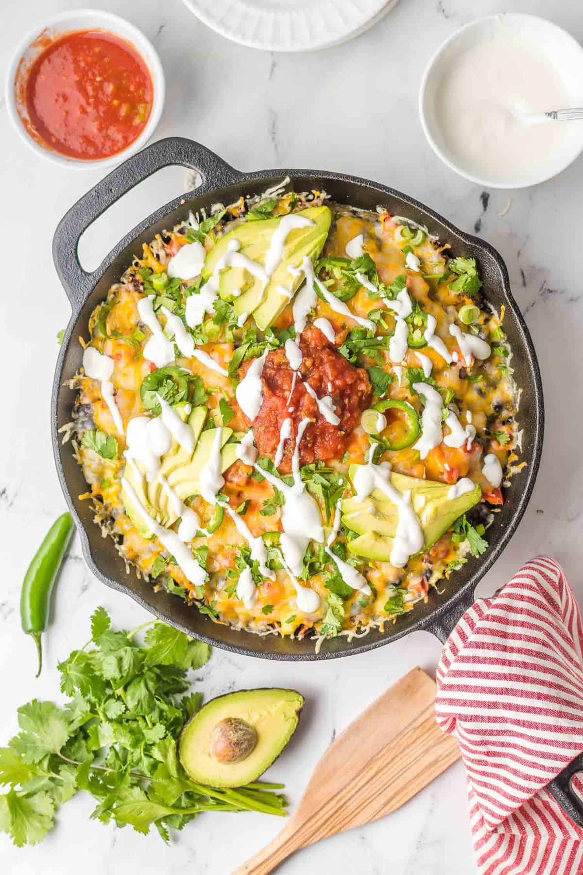 Nachos en una sartén de hierro fundido con los aderezos alrededor.