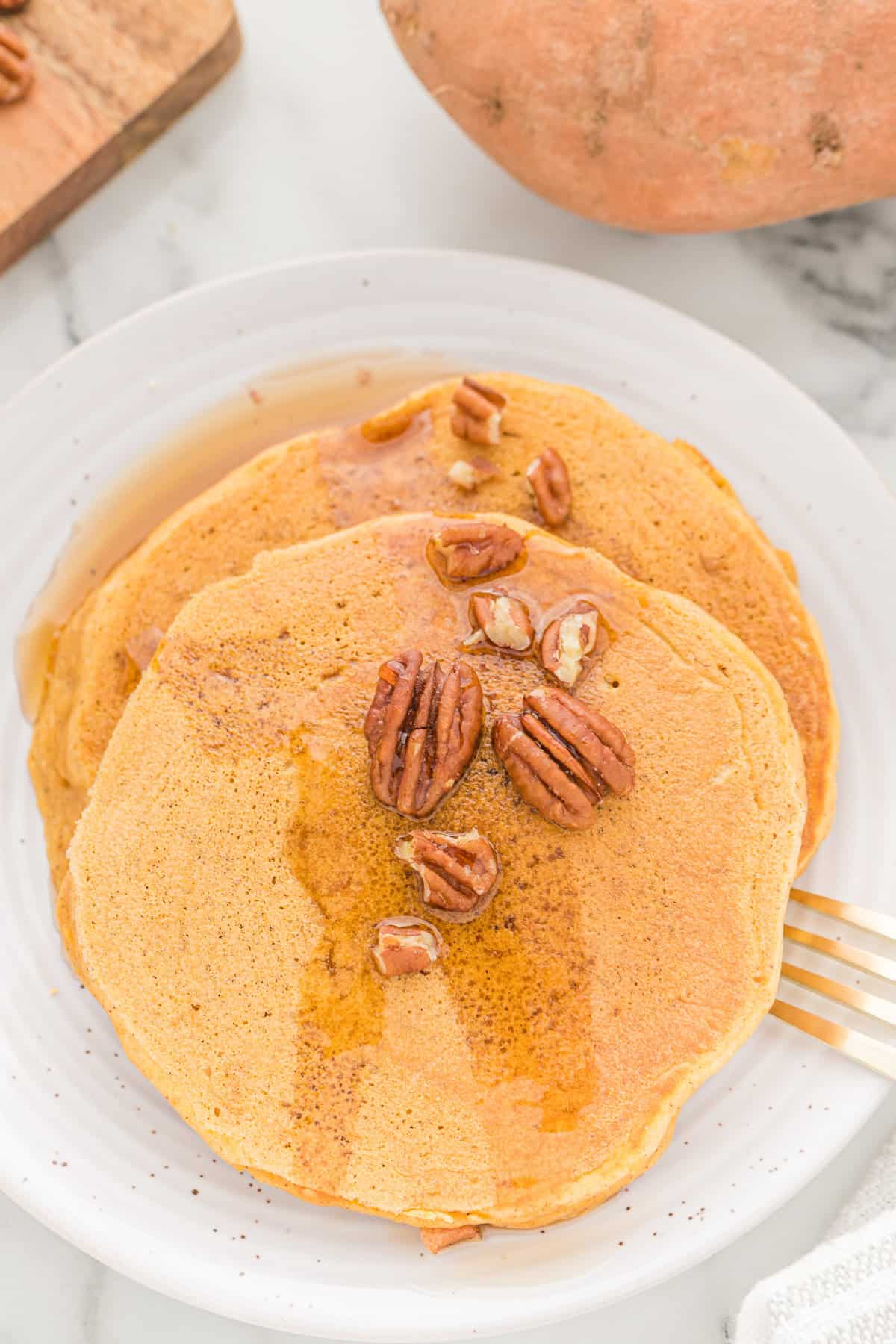 Panqueques de color naranja claro con jarabe de arce y nueces pecanas.