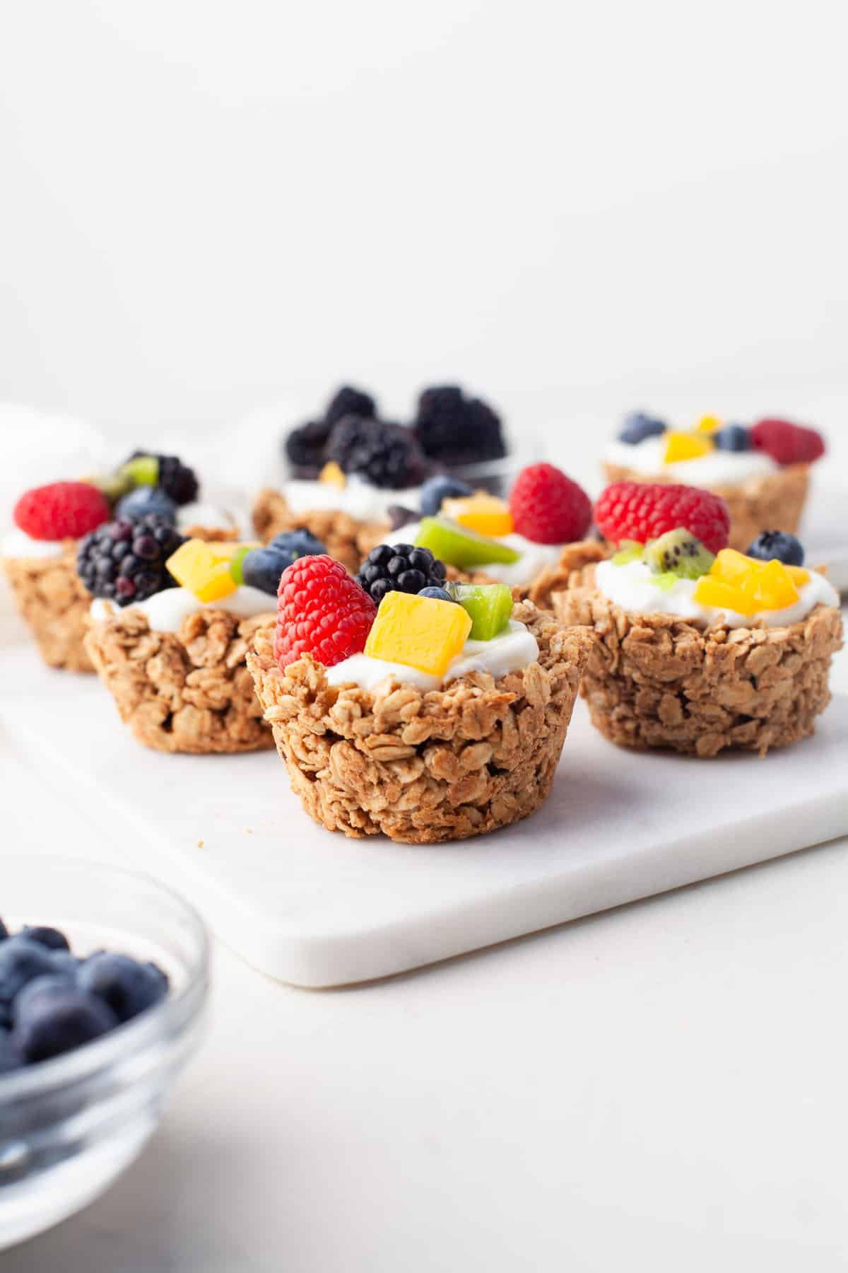 Cups de avena con fruta, sobre una superficie blanca.