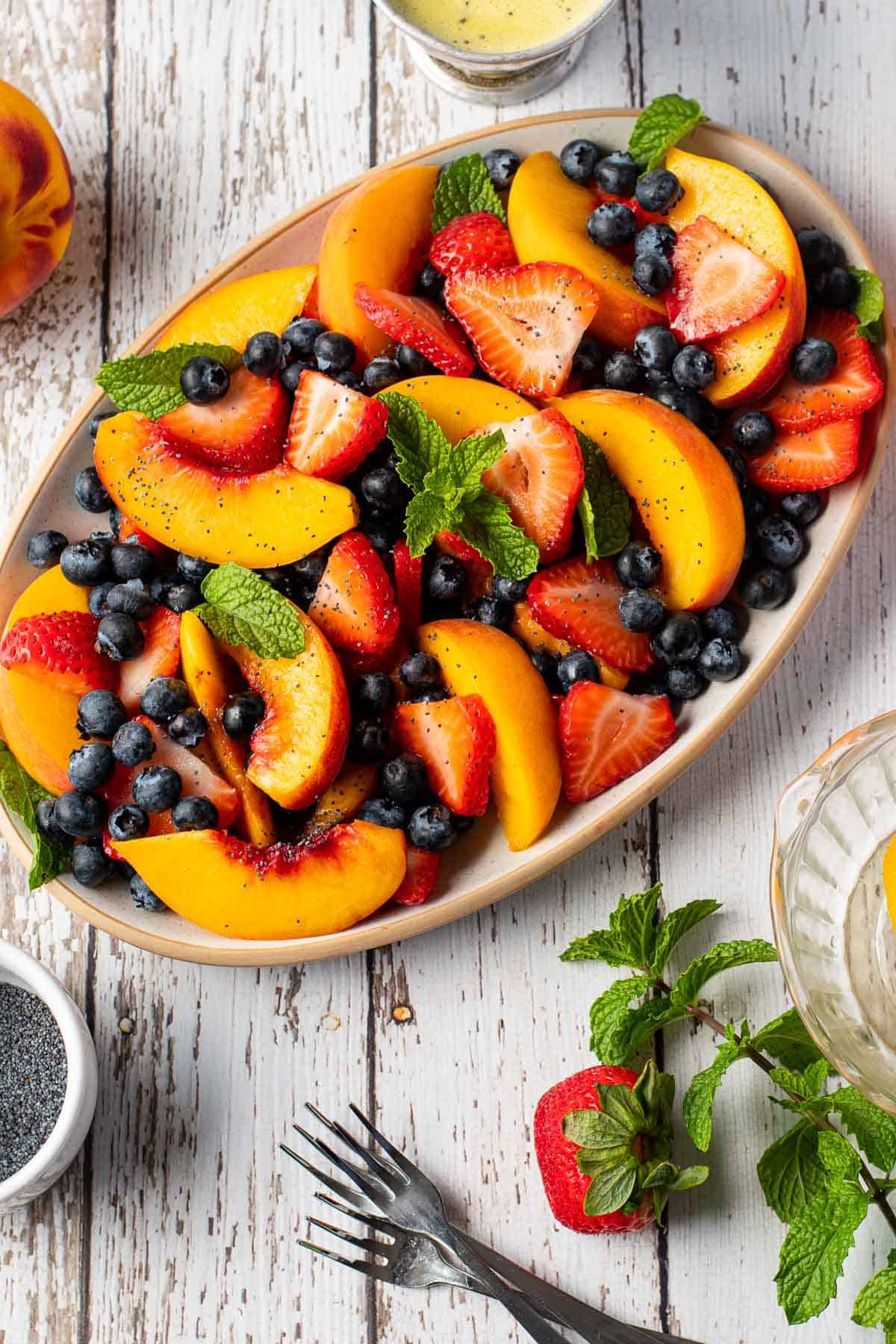 Ensalada con duraznos, fresas, arándanos y aderezo de semillas de amapola.