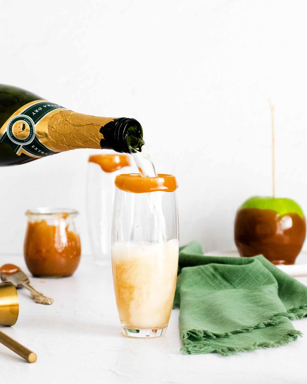 Vino espumoso siendo vertido en un vaso con borde de caramelo.