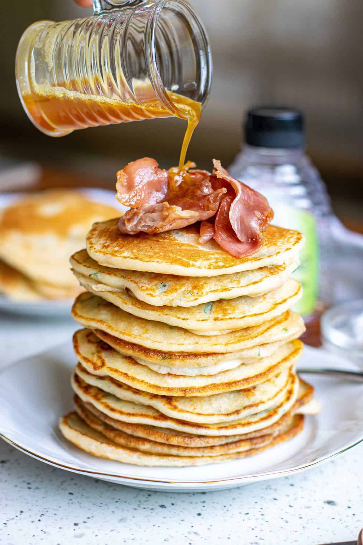 Brown butter being poured on a tall stack of pancakes.