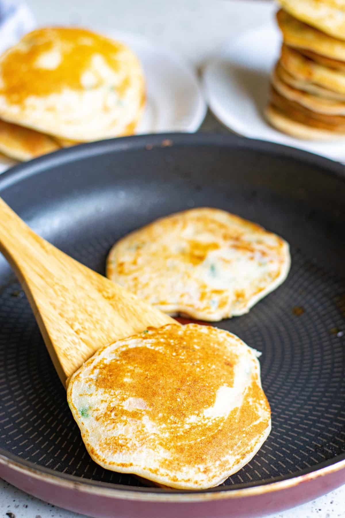 Cooked pancakes on a black frying pan.