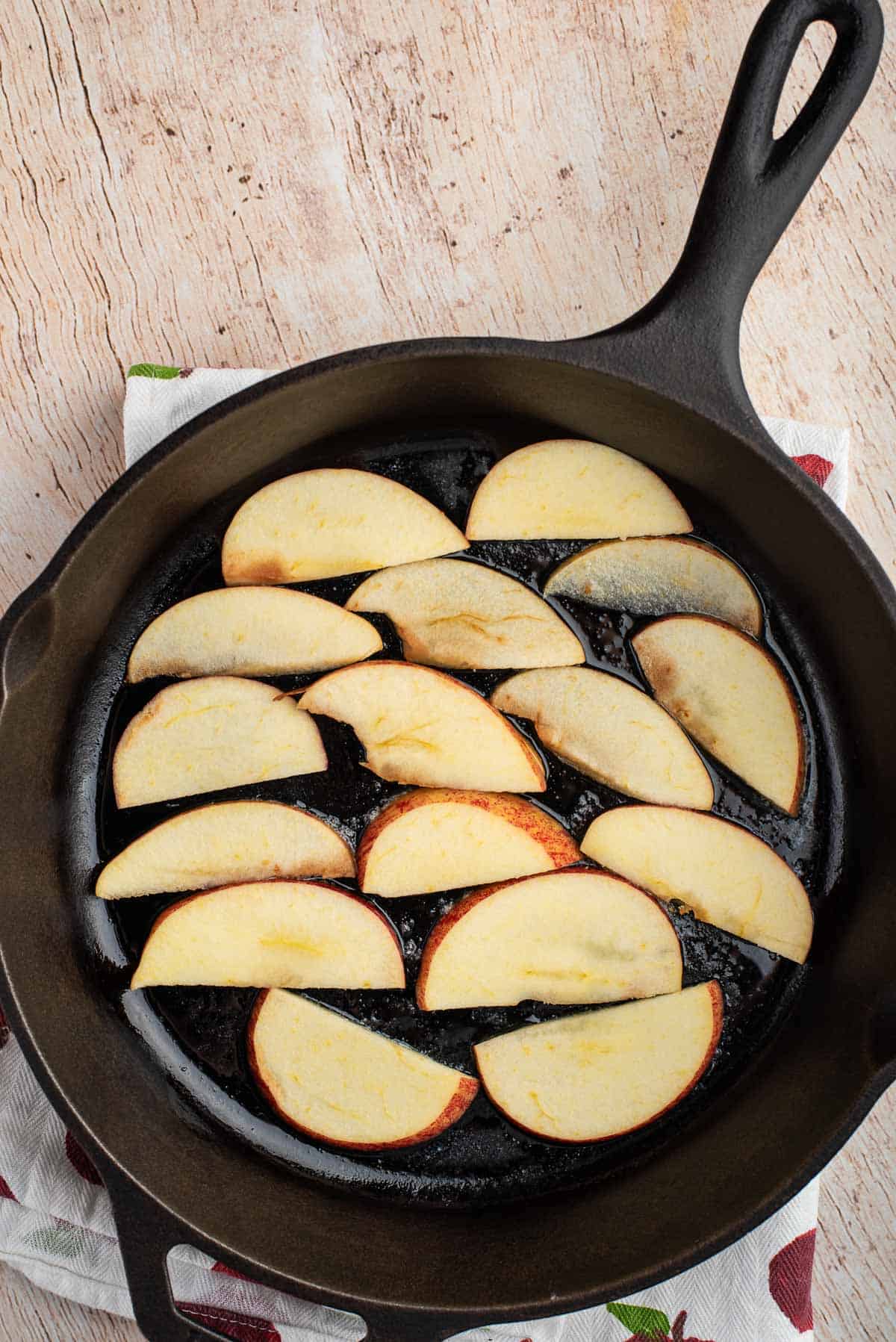 Manzanas en rodajas en el fondo de una sartén negra.