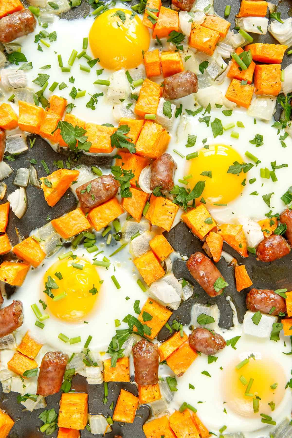 Primer plano de huevos, batatas y salchicha en una bandeja.