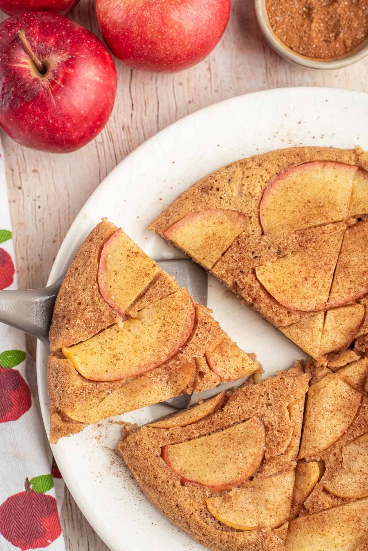 Una porción de panqueque de manzana siendo retirada de un plato con rebanadas adicionales.