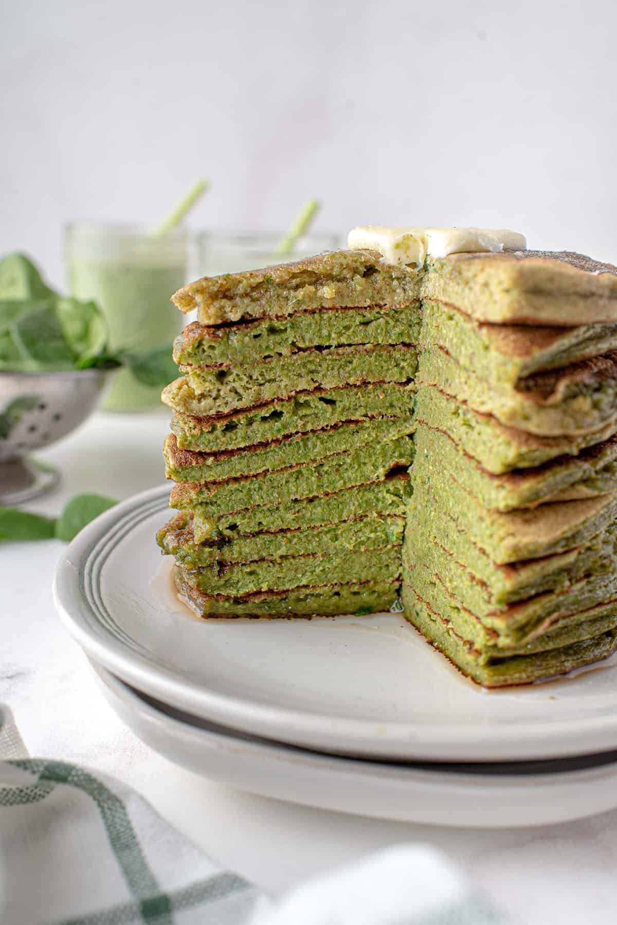 Torre de panqueques de smoothie verde con un trozo cortado para mostrar la textura y el color.