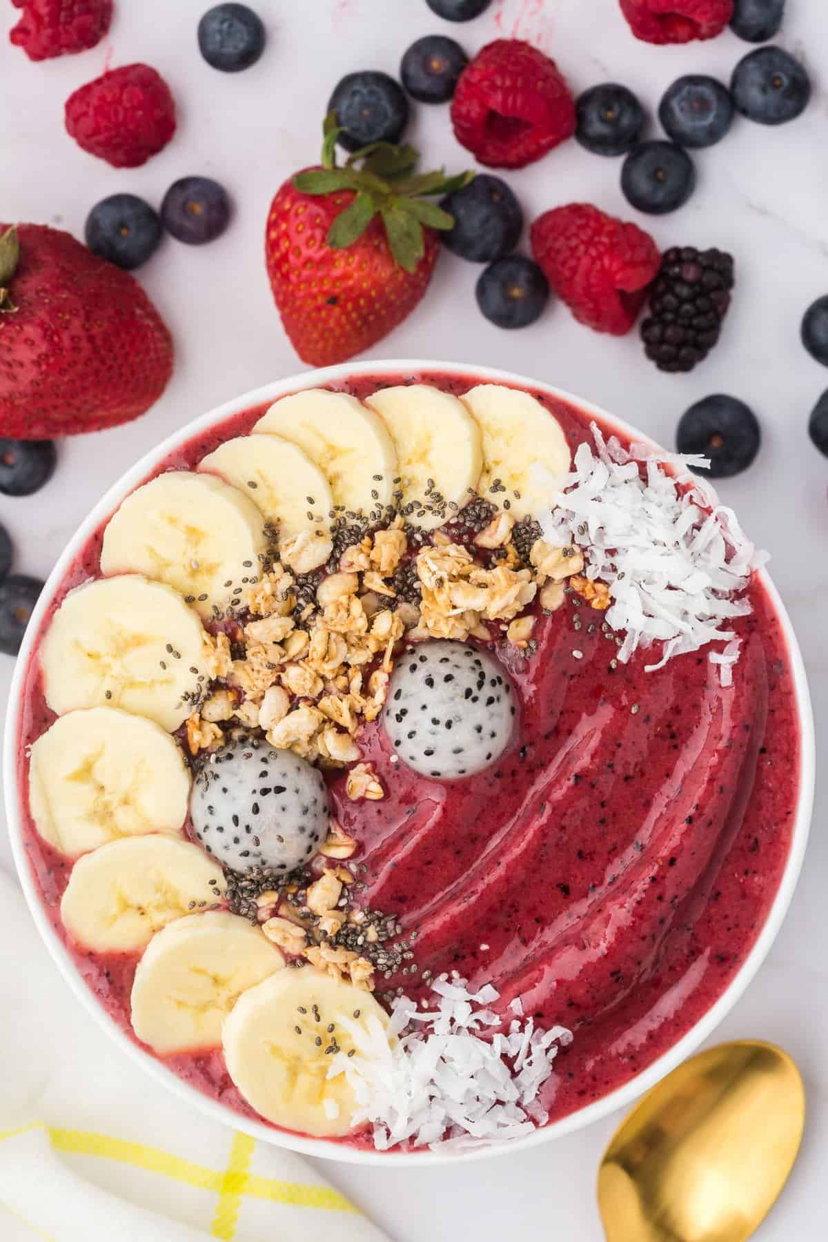 Tazón de batido de bayas decorado con plátanos, granola, coco.